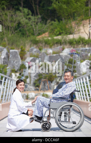 Ärztin im Gespräch mit einem Patienten im Rollstuhl sitzen Stockfoto