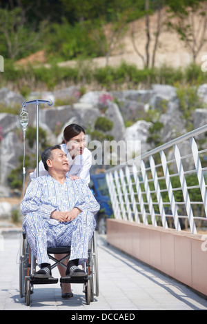 Ärztin, die ein Patient im Rollstuhl schieben Stockfoto