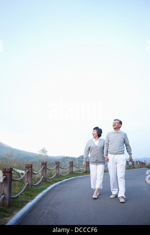 mittleren gealterten paar entlang einer leeren Straße hand in hand gehen Stockfoto