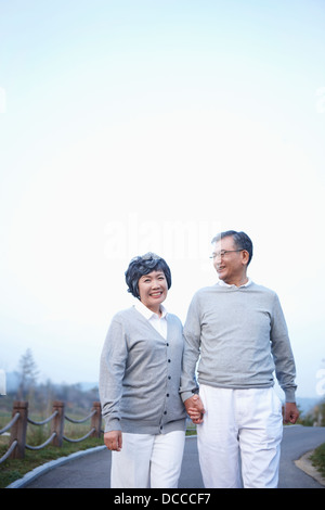 mittleren gealterten paar entlang einer leeren Straße hand in hand gehen Stockfoto