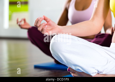Junge Frauen, die Yoga und Meditation im Fitness-Studio für bessere Fitness, kaukasischen und latina Stockfoto
