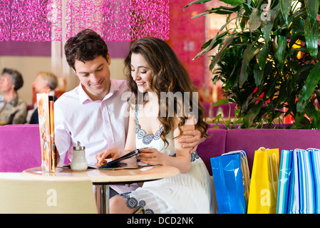 Junges Paar in einem Cafe oder Eis Stube, sie zeigen etwas in eine Tasche Stockfoto