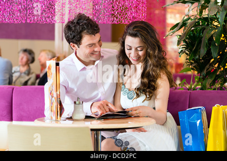 Junges Paar in einem Cafe oder Eis Stube, sie zeigen etwas in eine Tasche Stockfoto