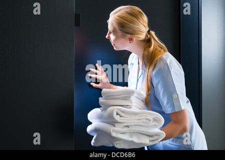 Zimmerservice - junge Zimmermädchen steht man vor einer Tür in einer Suite mit frischen Handtüchern Stockfoto