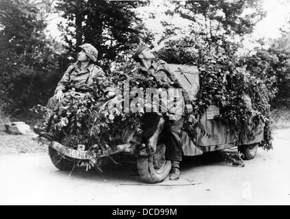 Mitglieder der deutschen Wehrmacht sind im Juli 1944 vor einem getarnten Fahrzeug in der Normandie in Frankreich abgebildet. Fotoarchiv für Zeitgeschichte Stockfoto