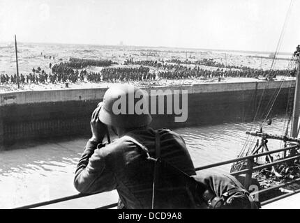 Ein Mitglied der deutschen Wehrmacht sieht sich im Juni 1940 im Hafen von Dünkirchen an der Westfront in Frankreich ein Fernglas an französischen und britischen Kriegsgefangenen an. Fotoarchiv für Zeitgeschichte Stockfoto