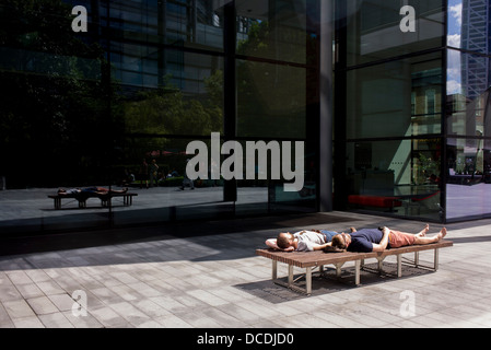 Zwei Männer schlafen im Sommersonnenschein, Austausch von einer Bank in der Fußgängerzone von Spitalfields im Zentrum von London. Stockfoto
