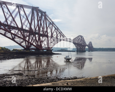 Her Eisenbahnbrücke von North Queensferry mit Boot auf Wattenmeer und Reflexion Stockfoto