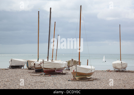 Hölzerne Segelboote vor Anker am steinigen Strand von Bier in Devon abgedeckt. Stockfoto