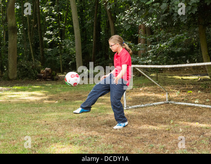 junges Mädchen Fußball kicken, im Hinterhof Stockfoto