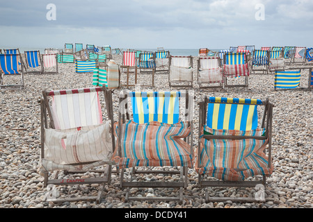 Liegestühle bei starkem Wind am Strand von Bier in Devon. Stockfoto