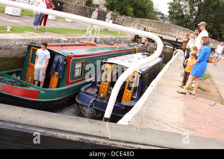 Menschen beobachten lange schmale Boote gehen durch eine Schleuse in Bradford On Avon Bestandteil der Kennet und Avon Kanal system Stockfoto