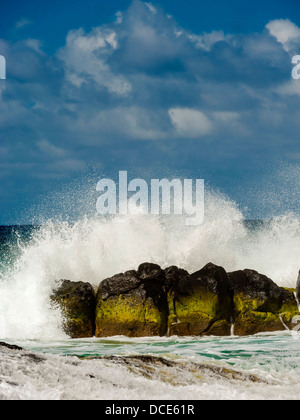 USA, Kauai, Hawaii. Eine Welle bricht auf den Felsen am Kauapea Strand, im Volksmund bekannt als Secret Beach. Stockfoto