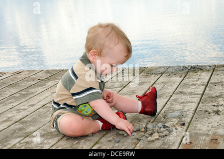 Ein kleiner Junge (im Alter von 15 Monaten) das Spiel mit einem Steinhaufen Stockfoto