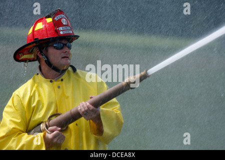 Ein Feuerwehrmann Besprühen mit Wasser aus einer Schlauchleitung Stockfoto