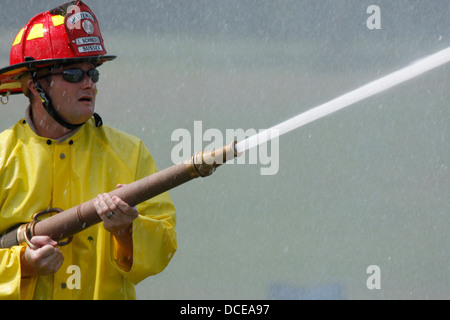 Ein Feuerwehrmann Besprühen mit Wasser aus einer Schlauchleitung Stockfoto