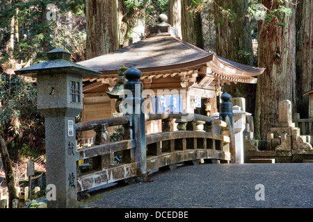 Naka no Hashi Holzbrücke, (mittlere Brücke), unter den Zedern auf dem gepflasterten Fußweg durch den japanischen alten Okunoin Friedhof bei Koya. Stockfoto