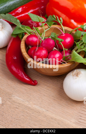Frische Radieschen in einer Holzschale mit anderen Gemüsesorten auf Hintergrund Stockfoto