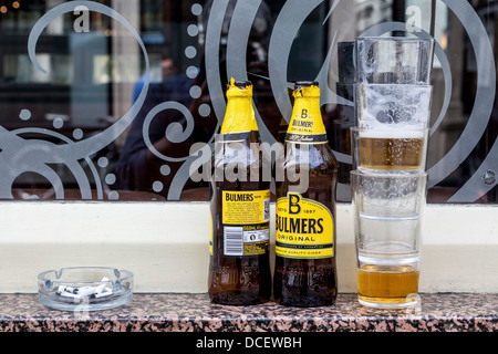 Bulmers Cider-Flaschen, halb leer verwendet Gläser und Aschenbecher, Zigarette enthält Zigarettenkippen auf Pub Fensterbank. Stockfoto