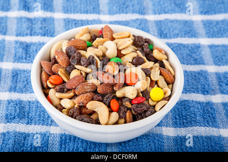 Eine Schüssel mit Trail mix mit Mandeln, Erdnüsse, Cashewnüsse, Rosinen und überdachte Pralinen Süßigkeiten Stockfoto