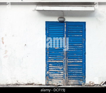 Hintergrundtextur mit Grunge blau Holztür auf weißen Wand Stockfoto