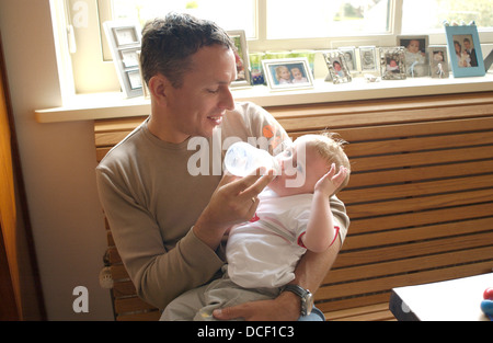 Vater ist mit der Flasche füttern sein kleiner Sohn Stockfoto