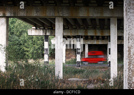 Roten van Auto geht schnell unter der alten Brücke Stockfoto