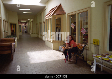 Eine attraktive, lächelnde Frau sitzt in kommerziellen inneren Flur im Abschnitt Virginia Highlands von Atlanta, Georgia, USA. Stockfoto