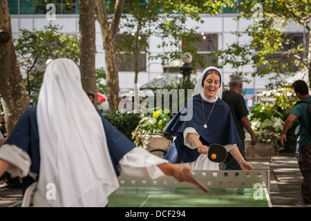 Nonnen von den Schwestern der Lebensordnung der katholischen Kirche spielen eine energetische Partie Tischtennis im Bryant Park in New York Stockfoto