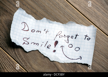 Vergessen Sie nicht, Smile - Hand, Schreiben von Text auf einem Blatt Papier auf Holz Hintergrund Stockfoto