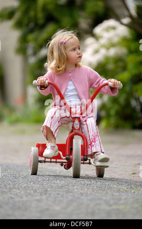 Kleines Mädchen auf einem Dreirad auf der Straße Stockfoto