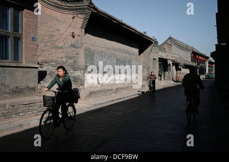 Straßenszene in Ping Yao, China. Menschen Radfahren. Stockfoto