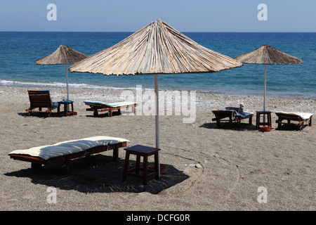 Sonnenliegen mit Sonnenschirmen in Lardos Beach in der Nähe von Lindos, Rhodos, Griechenland. Stockfoto