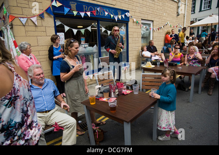 Nik Turner Gründungsmitglied von Hawkwind als Straßenmusikant unter Schar von BesucherInnen auf der Straße während der Brecon Jazz Festival 2013 Stockfoto