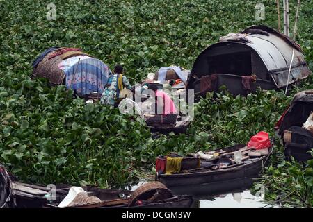 Bangladeshi Fluss gypsy arbeitet auf Ihrem Boot als Boot Mann versucht, seinen Weg durch die Wasserhyazinthe auf dem Fluss Buriganga in Dhaka zu machen. 2013. Stockfoto