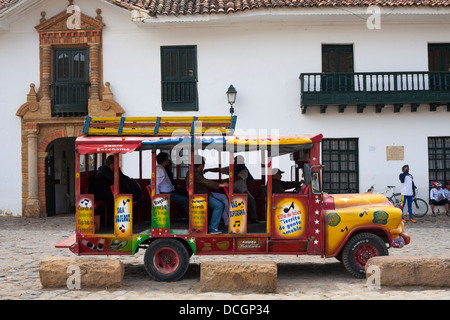 Ein buntes Oldtimer-Touristenbus nimmt Passagiere auf Touren in Villa de Leyva im Departamento von Boyacá in Kolumbien. Stockfoto