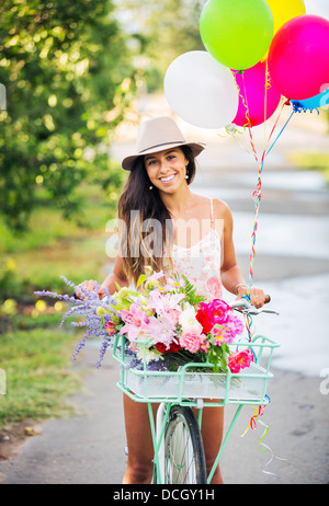 Schönes Mädchen Fahrrad mit Luftballons in Landschaft, Sommer-Lifestyle Stockfoto