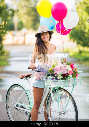 Schönes Mädchen Fahrrad mit Luftballons in Landschaft, Sommer-Lifestyle Stockfoto