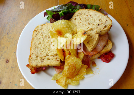 Guten Mittag Snack Schinken Sandwich im Kornhaus Brot mit Kartoffelchips und Salat Stockfoto