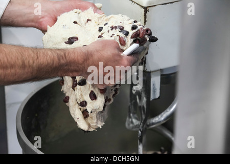 Bäcker knetet Brotteig in Rührschüssel geben Stockfoto