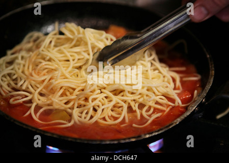 Zubereitung von Spaghetti und marinara Soße Sauce der Spaghetti hinzufügen Stockfoto