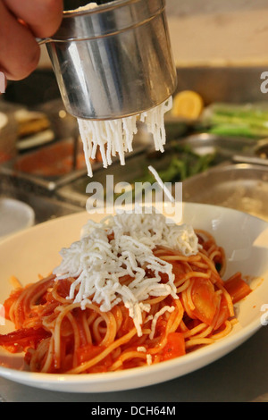 Zubereitung von Spaghetti und marinara Soße hinzufügen den Parmesan-Käse Stockfoto