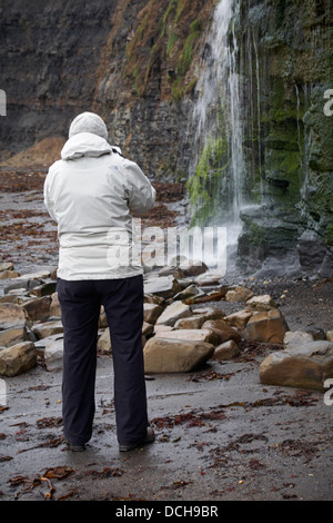 Frau fotografieren Wasserfall am Kimmeridge im Februar Stockfoto