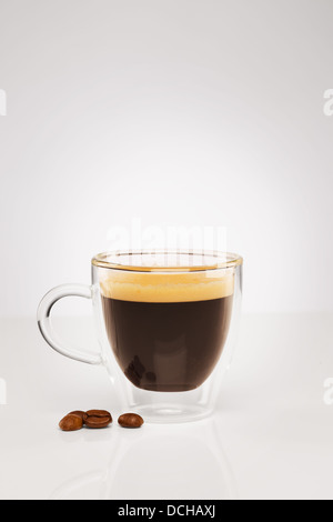 Espresso in einer Glasschale mit Kaffeebohnen auf grauem Hintergrund Stockfoto