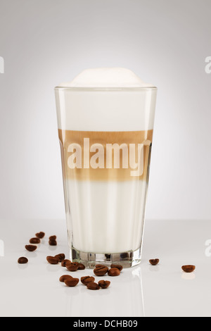 ein original Latte Macchiato mit Kaffeebohnen auf grauem Hintergrund Stockfoto