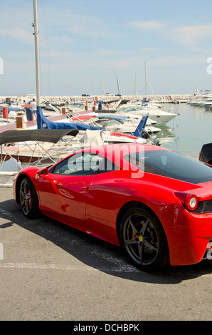 Ferrari 458 Italia parkte vor einer Reihe von Yachten in Puerto Banus, Marbella, Spanien. Stockfoto