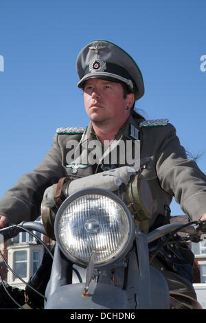 Tim Bateson aus Preston, auf einem russischen Motorrad-Ural sitzend. URAL ist ein einzigartiges klassisches Seitenwagen Motorrad und Seitenwagen. Tim ist ein Reenaktor, der das Kostüm eines deutschen Großsoldaten auf dem Lytham 1940er Kriegsfestival trägt, 1940s Ära, 40er Kriegswochenende, Kriegsnachstellung auf Lytham Green, Lancashire, Großbritannien. Stockfoto