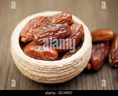 Leckere Datteln in Schälchen auf Holzoberfläche Stockfoto