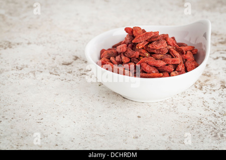 kleine Keramikschale getrocknete Goji Beeren vor dem Hintergrund der keramischen Fliese mit einem Textfreiraum Stockfoto