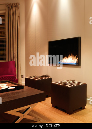 Couchtisch mit Sitzgelegenheiten und modernen Feuer in Privathaus, London, UK. Stockfoto